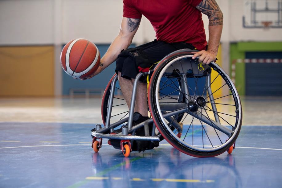 A wheelchair user playing basketball on a blue court.