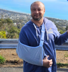 A YAY Today participant, arm in sling, coastal backdrop